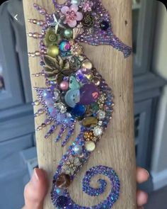 a person is holding up a piece of wood with beads and other things on it