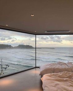 two beds in a room with large windows overlooking the ocean