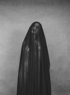 a woman in a long black veil standing with her hands on her hips and looking at the camera