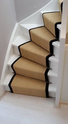 there is a stair case with black trim on the bottom and beige carpet down the side