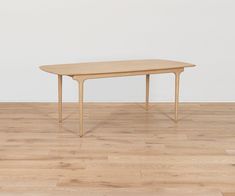 a wooden table sitting on top of a hard wood floor next to a white wall