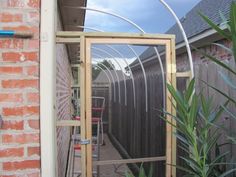 an open door in the side of a brick building next to a green planter