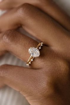 a close up of a person's hand wearing a gold ring with a diamond