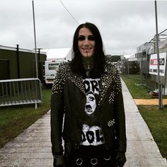 a person with long hair and piercings standing on a sidewalk