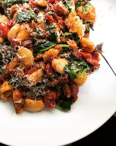 a white plate topped with pasta and spinach