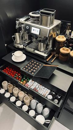 an assortment of coffee and espresso machines on display in a black cabinet with drawers