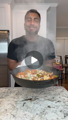 a man standing in front of a wok filled with food