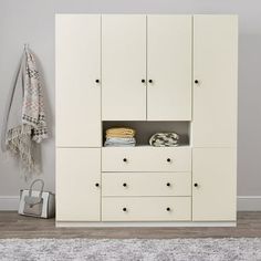 a white cabinet with two drawers and some towels hanging on the wall next to it