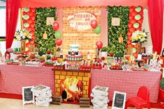 a red and white table topped with a fire place next to a brick fireplace covered in balloons