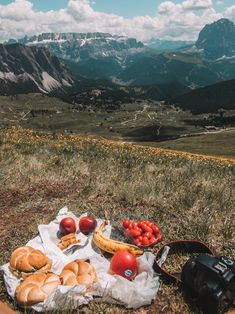 a bagel and some fruit on the ground with mountains in the background