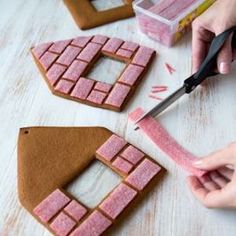 someone cutting out gingerbread shapes with a pair of scissors on a table next to them