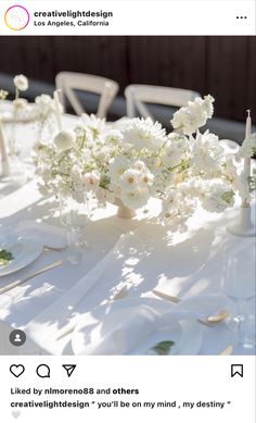 the table is set with white flowers and place settings