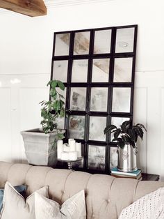 a living room with a couch, mirror and potted plant on the table in front of it