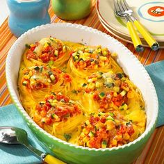 a casserole dish filled with pasta and vegetables on a table next to silverware