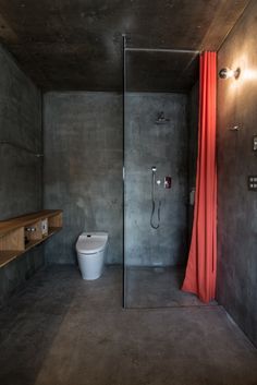 a bathroom with a toilet, shower and sink in it's concrete wall space