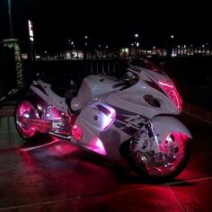 a white motorcycle parked on top of a wooden floor next to a parking lot at night