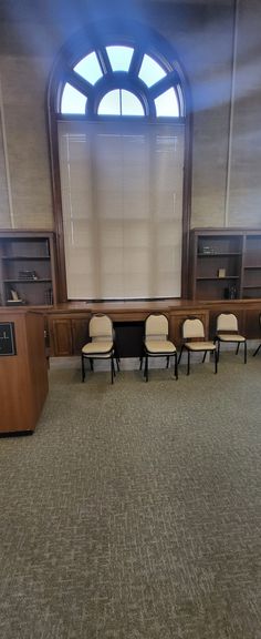 an empty courtroom with chairs and desks in front of a large window that looks out onto the street