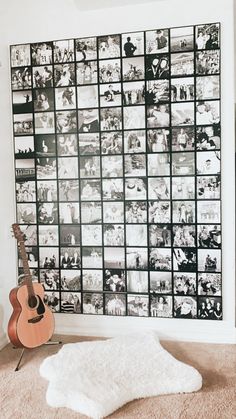 a guitar sitting on the floor in front of a wall covered with black and white photos