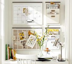 a white desk and chair in front of a wall with calendars on the walls