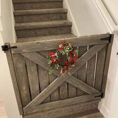 a wooden gate with a wreath on the top and stairs leading up to an upper level