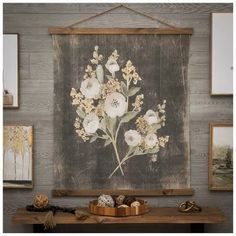 a painting hanging on the wall above a wooden table with flowers and other items in front of it