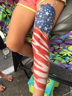 a woman sitting in a chair with an american flag painted on her leg and arm