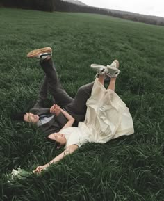 a bride and groom laying in the grass with their feet up on each other's shoulders