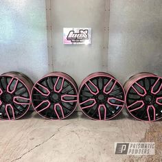 four black and pink wheels are lined up against the wall