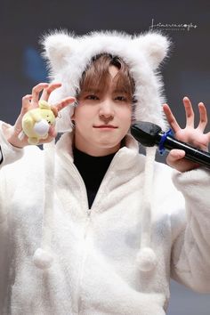 a young man wearing a furry white hoodie and holding a toy in his hands