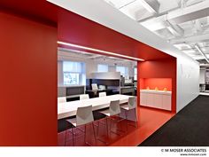 an office with bright red walls and white chairs in the center, along with black carpeted flooring