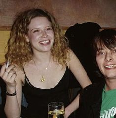 two people sitting at a table with drinks and food in front of them smiling for the camera