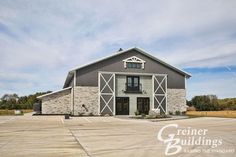 an empty parking lot in front of a large gray barn with white trim and windows