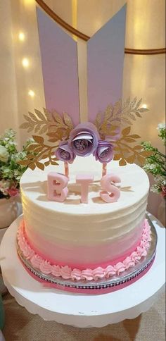 a white cake with pink frosting and two purple flowers sitting on top of it