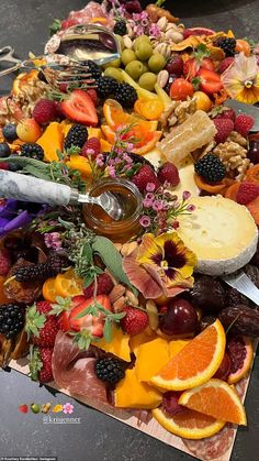 an assortment of fruits and cheeses are arranged on a cutting board with a knife