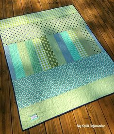 a green and blue quilt sitting on top of a wooden floor