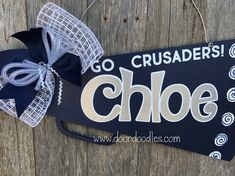 a close up of a sign with a bow on it's head hanging from a wooden fence