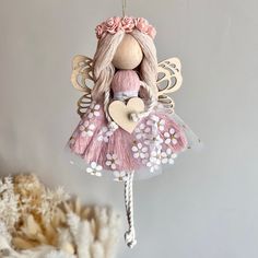 a pink and white fairy ornament hanging from a string