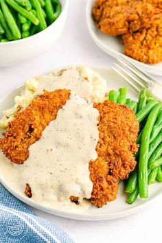 fried chicken with gravy and mashed potatoes on a plate next to green beans