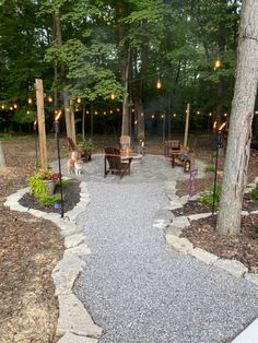 an outdoor area with benches and lights in the trees, surrounded by graveled walkway