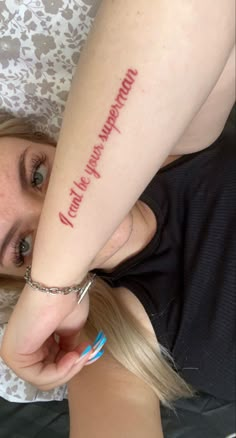 a woman laying on top of a bed with a tattoo on her arm and hand