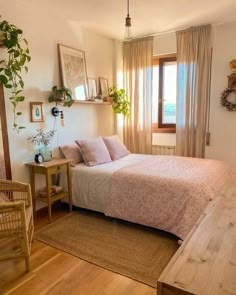 a bed sitting in a bedroom next to a wooden table and chair near a window