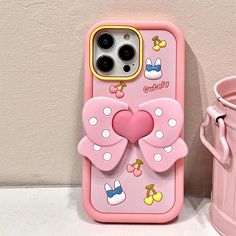 a pink iphone case with a bow on it next to a pink watering can and cup