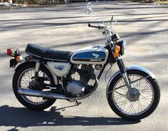 a motorcycle is parked on the street in front of some trees and bushes, with no one around it