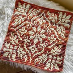 a red and white rug sitting on top of a fur covered floor