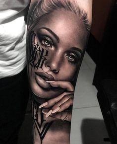 a woman's face and hands with tattoos on her arm, in black and white