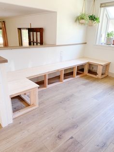 an empty room with wooden benches and planters on the windowsill, in front of a window sill