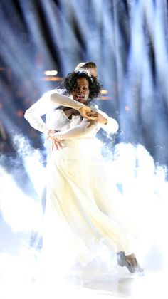 a woman in a white dress is dancing on stage