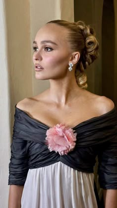 a woman wearing a black and white dress with a flower in her hair is looking off to the side