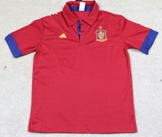 a red and blue polo shirt with the crest of spain on it's chest