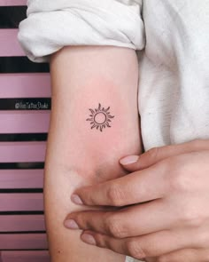 a woman's arm with a small sun tattoo on the left side of her arm